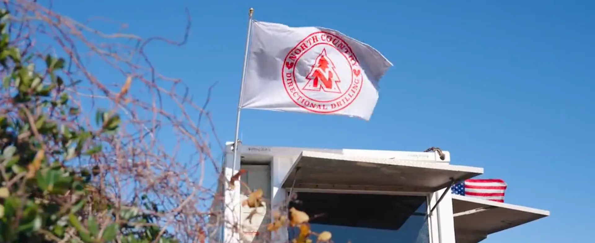 The North Country Directional Drilling flag flying on a job site, with an American flag below it